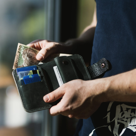 Close-up of hands holding an open wallet with cash and credit cards, symbolizing easy payment